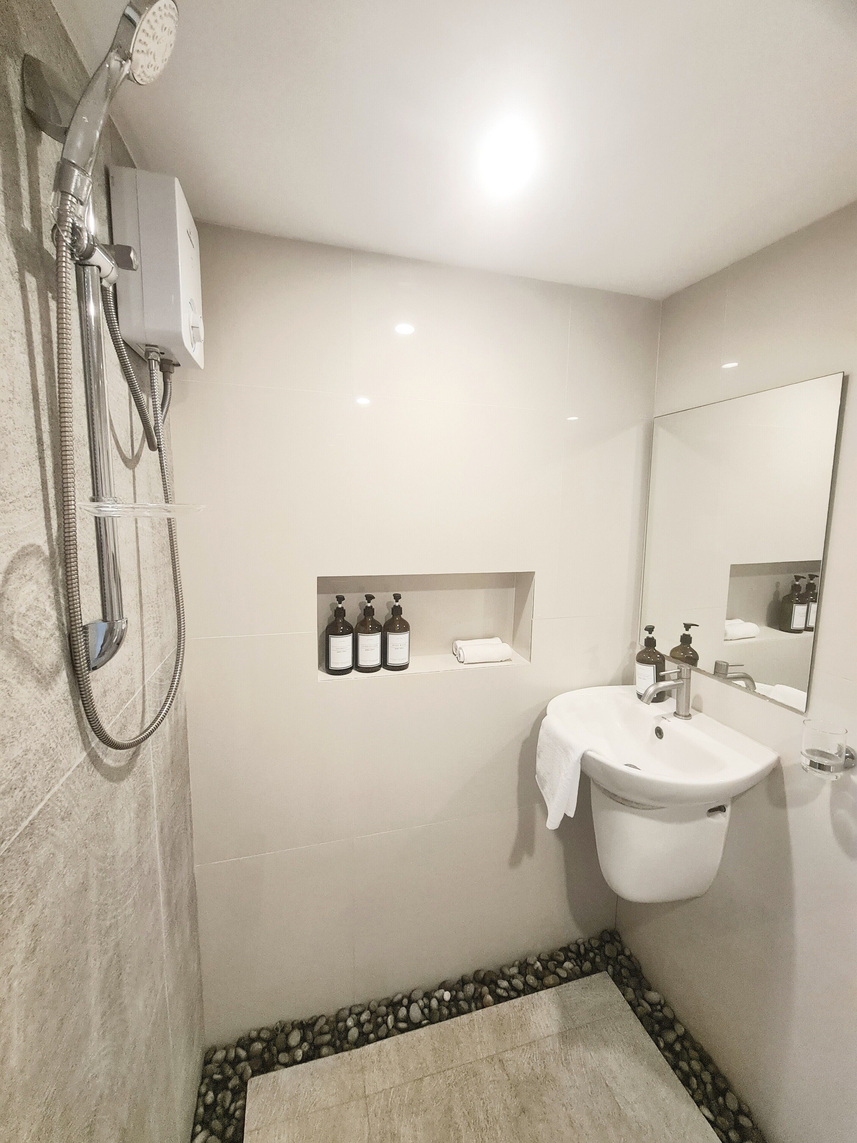 A modern bathroom with a shower, sink, and mirror.