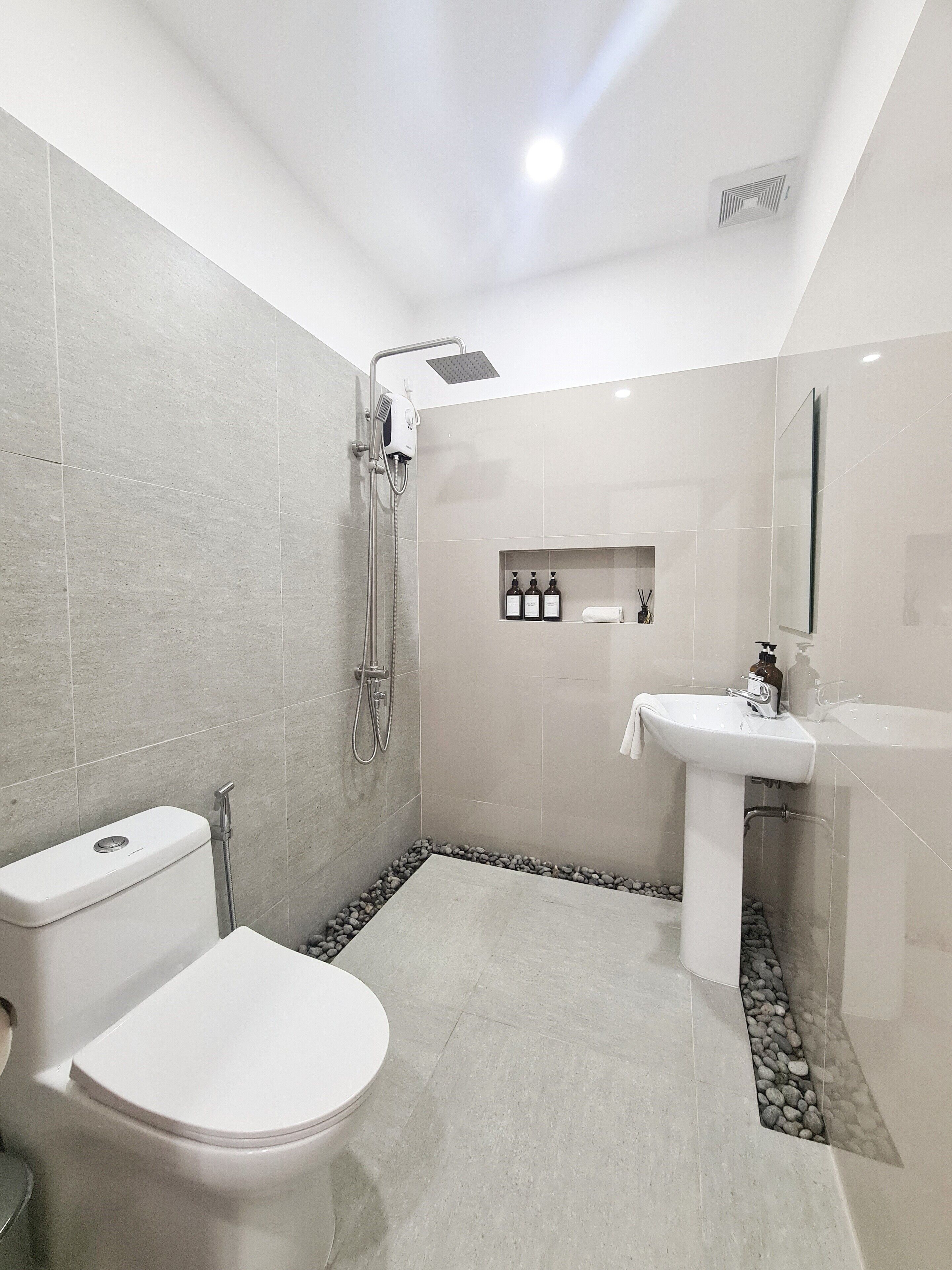 A modern bathroom with a toilet, shower, and sink.
