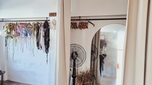 A room with wooden beams, a ceiling fan, and a clothing rack with various garments. - 148 Guesthouse and Resort (Alaminos)