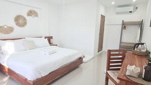 A modern bedroom with a wooden bed, a dining table with chairs, and a small plant. - 148 Guesthouse and Resort (Alaminos)