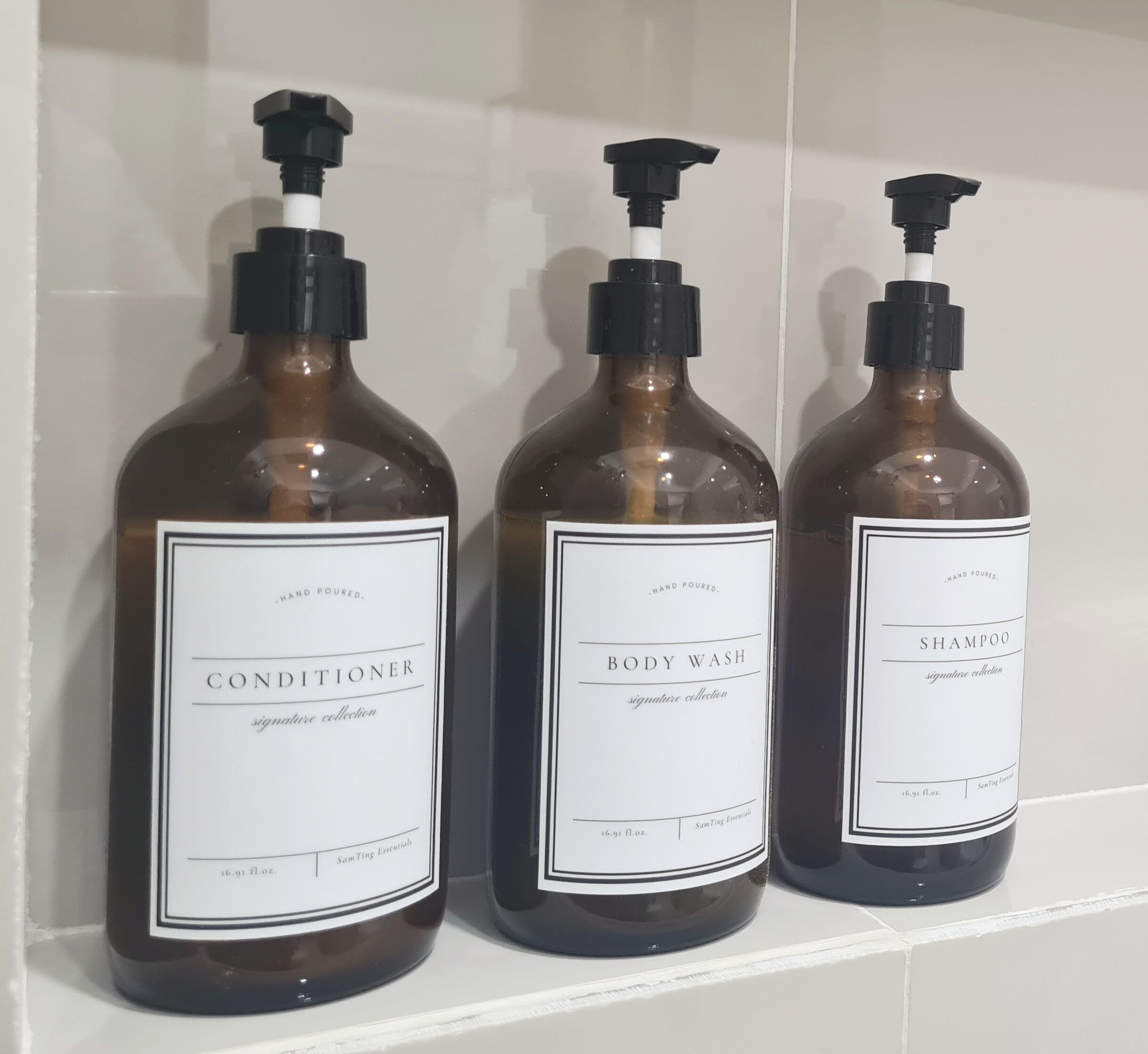 Three bottles of hand-poured body wash and conditioner on a shelf.
