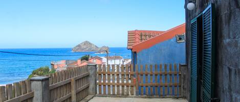 A coastal property with a view of the sea, a wooden gate, and a building with a blue facade.