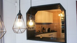 A kitchen with a black countertop and white tiled backsplash. There are two pendant lights hanging above the counter. - House 37North (Ponta Delgada)