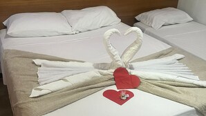 A hotel room with two beds, each with white linens and a brown blanket. A decorative towel arrangement in the shape of a swan with a red heart is placed on the bed in the foreground. - Pousada In Paradiso (Aracruz)