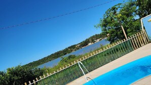 A swimming pool with a clear view of a lake and hills in the background. - Pousada In Paradiso (Aracruz)