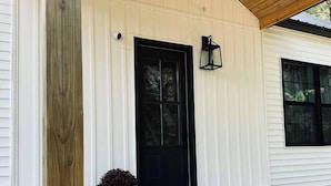 A wooden deck with a black door and a potted plant.