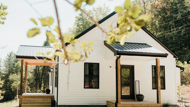 A small, single-story cabin with a sloped roof and a porch.