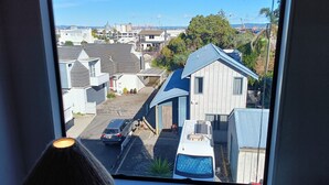 A view through a window of a residential area with houses, a street, and a clear sky. - Best position in Mt Maunganui, quiet yet central. 300 m from beach & Pilot Bay (Mount Maunganui)