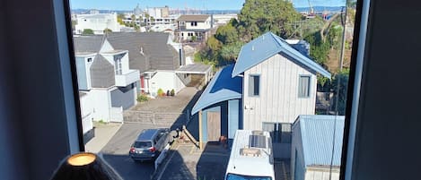 A view through a window of a residential area with houses, a street, and a clear sky.