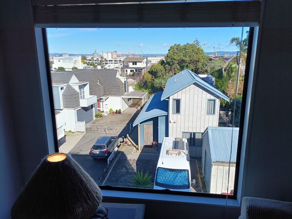 A view through a window of a residential area with houses, a street, and a clear sky. - Best position in Mt Maunganui, quiet yet central. 300 m from beach & Pilot Bay (Mount Maunganui)