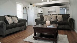A living room with two dark sofas, a wooden coffee table, and a white rug.