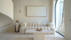 A modern living room with a white sofa, a coffee table, and a large window. - Villa Eyla (Canggu)