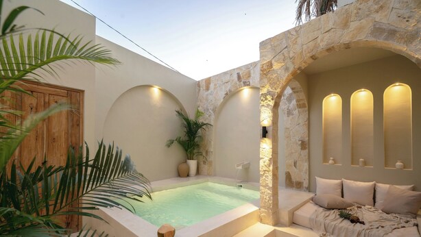 A spa area with a hot tub, a stone archway, and a seating area with cushions. - Villa Eyla (Canggu)