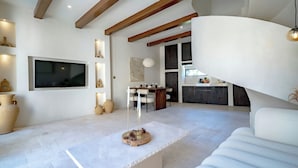 A modern living room with a white sofa, a dining area with a wooden table, and a kitchen area with a countertop. - Villa Eyla (Canggu)