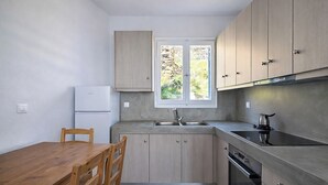 Eine kleine Küche mit Holzausstattung, einem eingebauten Ofen, einem Spülbecken und einem Fenster mit Blick auf Grünflächen.