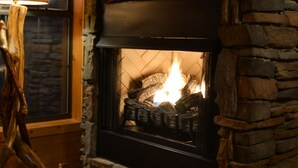 A stone fireplace with a television mounted above it. - Cozy Bear: A Dreamy Cabin Hideout for Two, Gatlinburg & Pigeon Forge - SPECIALS (Pigeon Forge)