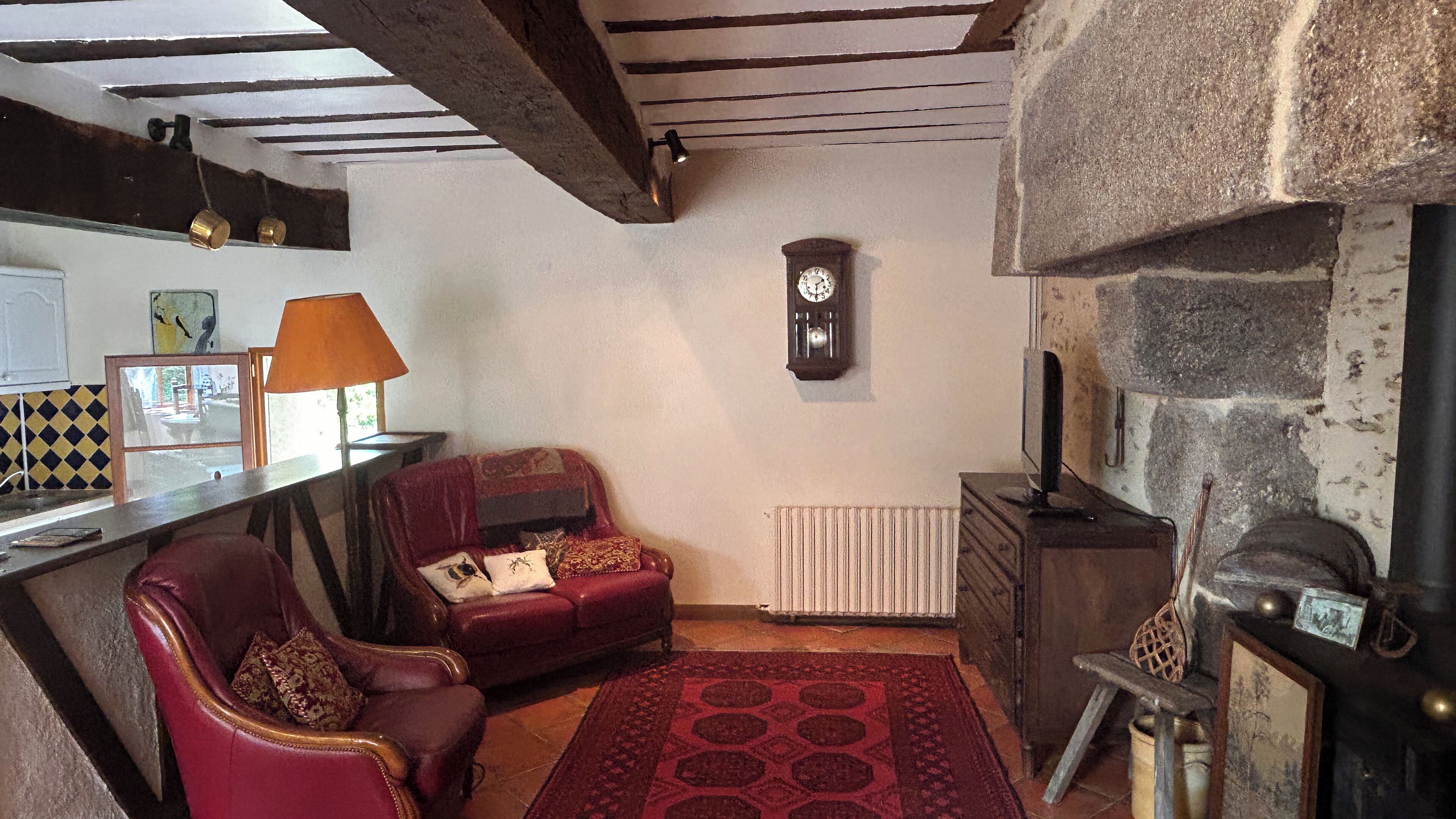 A cozy living room with a fireplace, a red sofa, and a patterned rug.