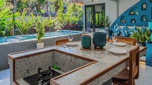 Un comedor moderno con vista a la piscina, asientos al aire libre y ventilador de techo.