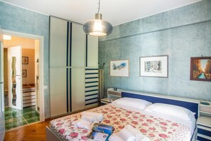 A bedroom with a bed, a wardrobe, a desk, and a hanging light fixture. - Bilocale Vista Mare con Piscina SeaView Balcony + Pool, Sanremo, Italy (Sanremo)