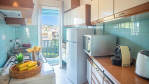 A kitchen with a refrigerator, microwave, coffee maker, and a window overlooking a balcony.