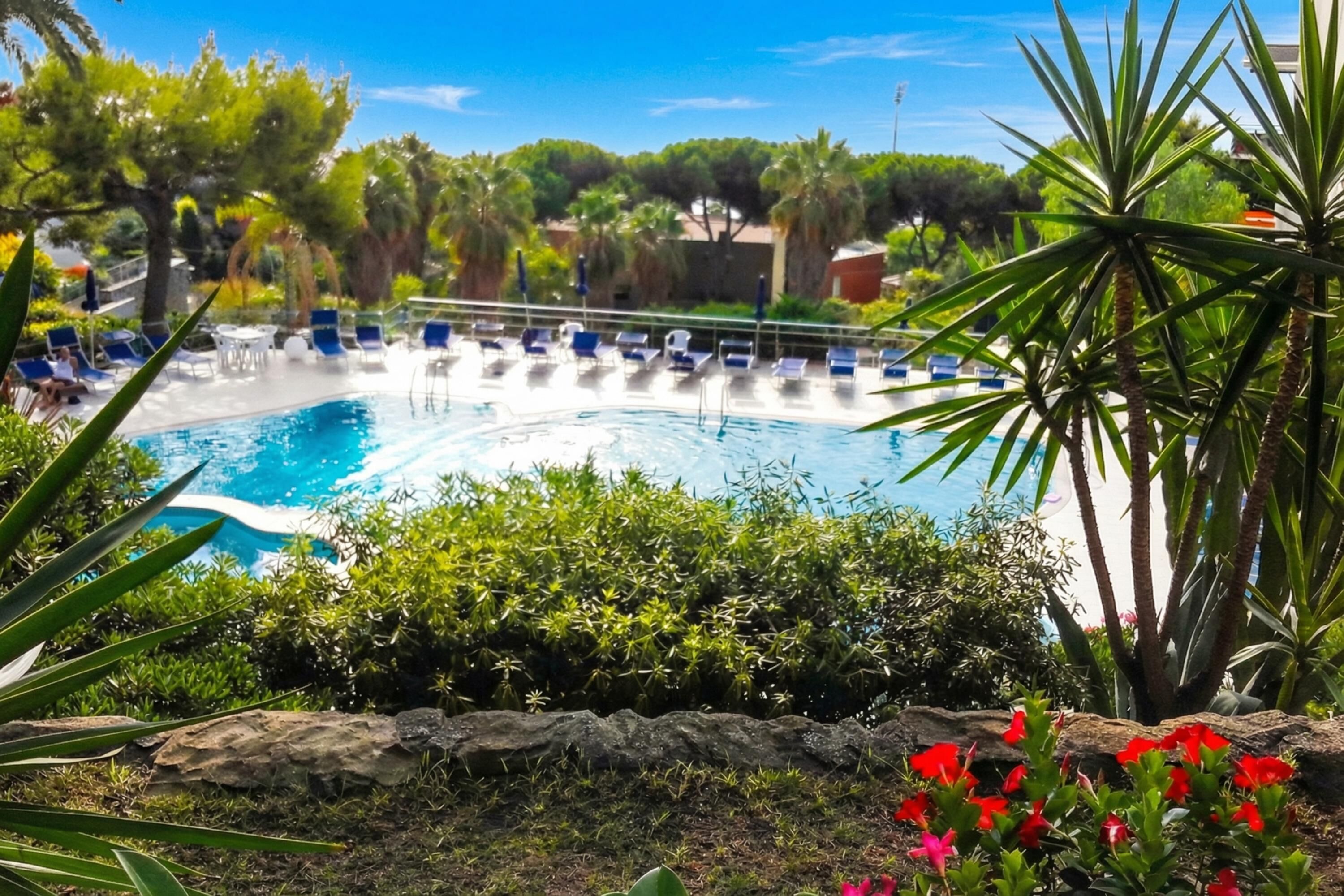 Una piscina con sillas de descanso y un muro de piedra.