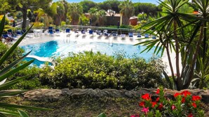 A pool with lounge chairs and a stone wall.