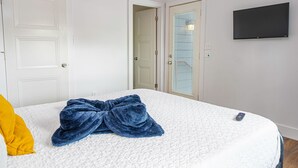 A bedroom with a bed, a blue blanket, a remote control, and a TV on the wall. - Cozy and Gorgeous 2BR 1BA Near Amazing Downtown (San Antonio)