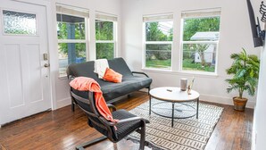A room with a black leather sofa, a round coffee table, a potted plant, and large windows. - Cozy and Gorgeous 2BR 1BA Near Amazing Downtown (San Antonio)