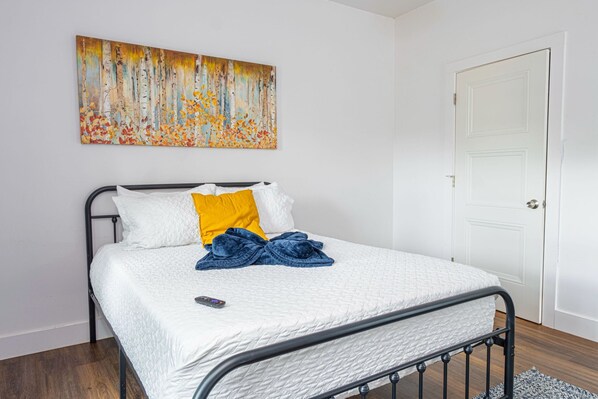 Une chambre Ă coucher avec un lit, un tableau et une porte.