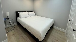 Een netjes ingerichte slaapkamer met een bed, nachtkastje en een deur.