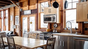 A wooden interior with a dining table, chairs, a stove, and a sink. - Lakeside Cabin on Private Lake! Perfect for families and couples getaway. (Cascade)