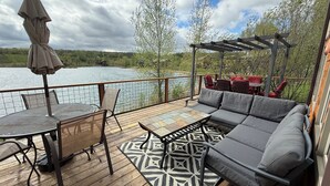 A deck with a sofa, chairs, a table, and an umbrella. - Lakeside Cabin on Private Lake! Perfect for families and couples getaway. (Cascade)