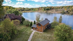 A lakeside property with a main house and a smaller building, surrounded by trees and a clear view of the lake. - Lakeside Cabin on Private Lake! Perfect for families and couples getaway. (Cascade)