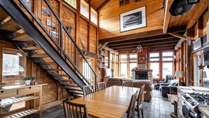 A wooden cabin interior with a dining area, kitchen, and a staircase. - Lakeside Cabin on Private Lake! Perfect for families and couples getaway. (Cascade)
