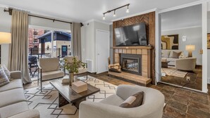 A modern living room with a fireplace, a large flat-screen TV, and comfortable seating. - Central Park City | Pool + Patio Access (Park City)