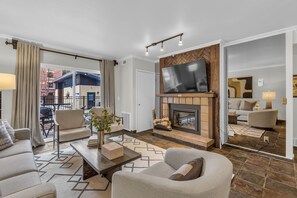 A modern living room with a fireplace, a large flat-screen TV, and comfortable seating. - Central Park City | Pool + Patio Access (Park City)