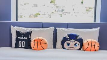 A bed with two pillows, one with a basketball and the other with a cartoon character.