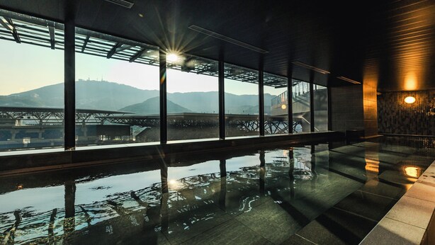 Piscina interior moderna con vista a un puente y montañas.