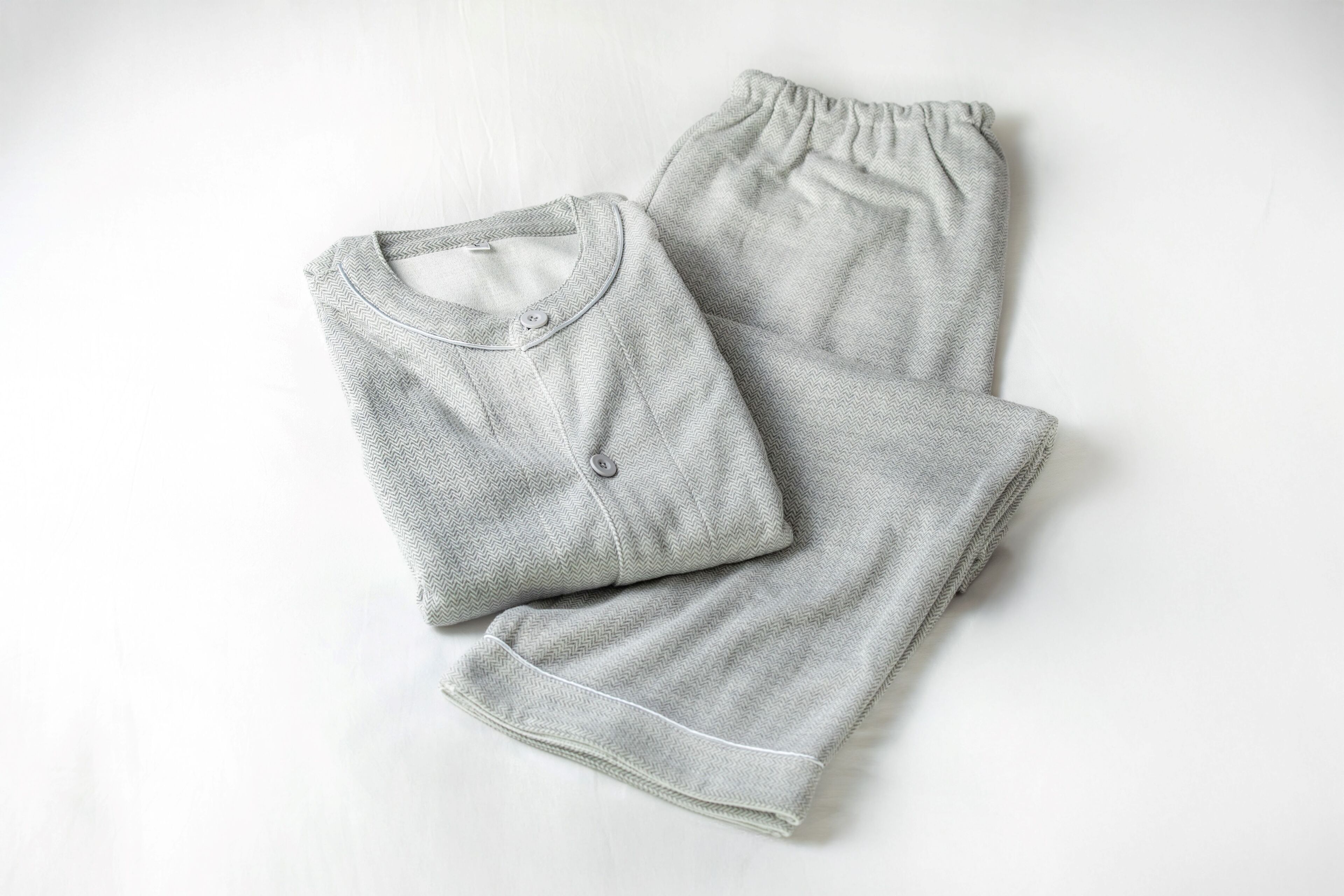 A pair of light grey, ribbed, short-sleeved pants and a matching top laid out on a white surface.