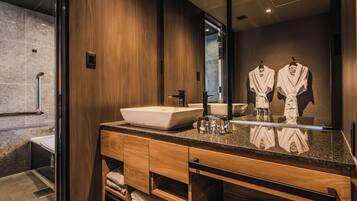 A modern bathroom with a large mirror, wooden vanity, and a glass shower enclosure.