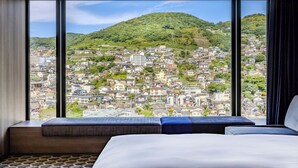 Habitación de hotel con un ventanal que ofrece vistas a una ciudad densamente poblada en una ladera.