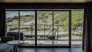 Una habitación moderna con un amplio ventanal corredero que da a un balcón con vistas a la ciudad.