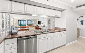 A modern kitchen with white cabinetry, stainless steel appliances, and a granite countertop.