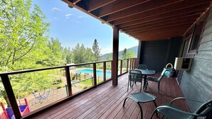 A wooden deck with a view of a swimming pool and trees. - Ski-In/Ski-Out Condo | Hot Tub + Mountain Views (Lutsen)
