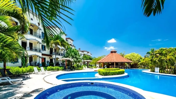 Un resort con una piscina grande, sillas de descanso y un pabellón.