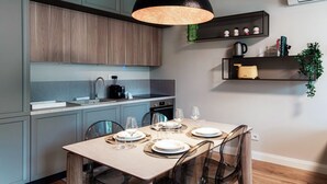 A modern kitchen with grey cabinets, a wooden dining table set for four, and a black pendant light. - Marinetti Suite 7 - MyHomeinComo (Como)