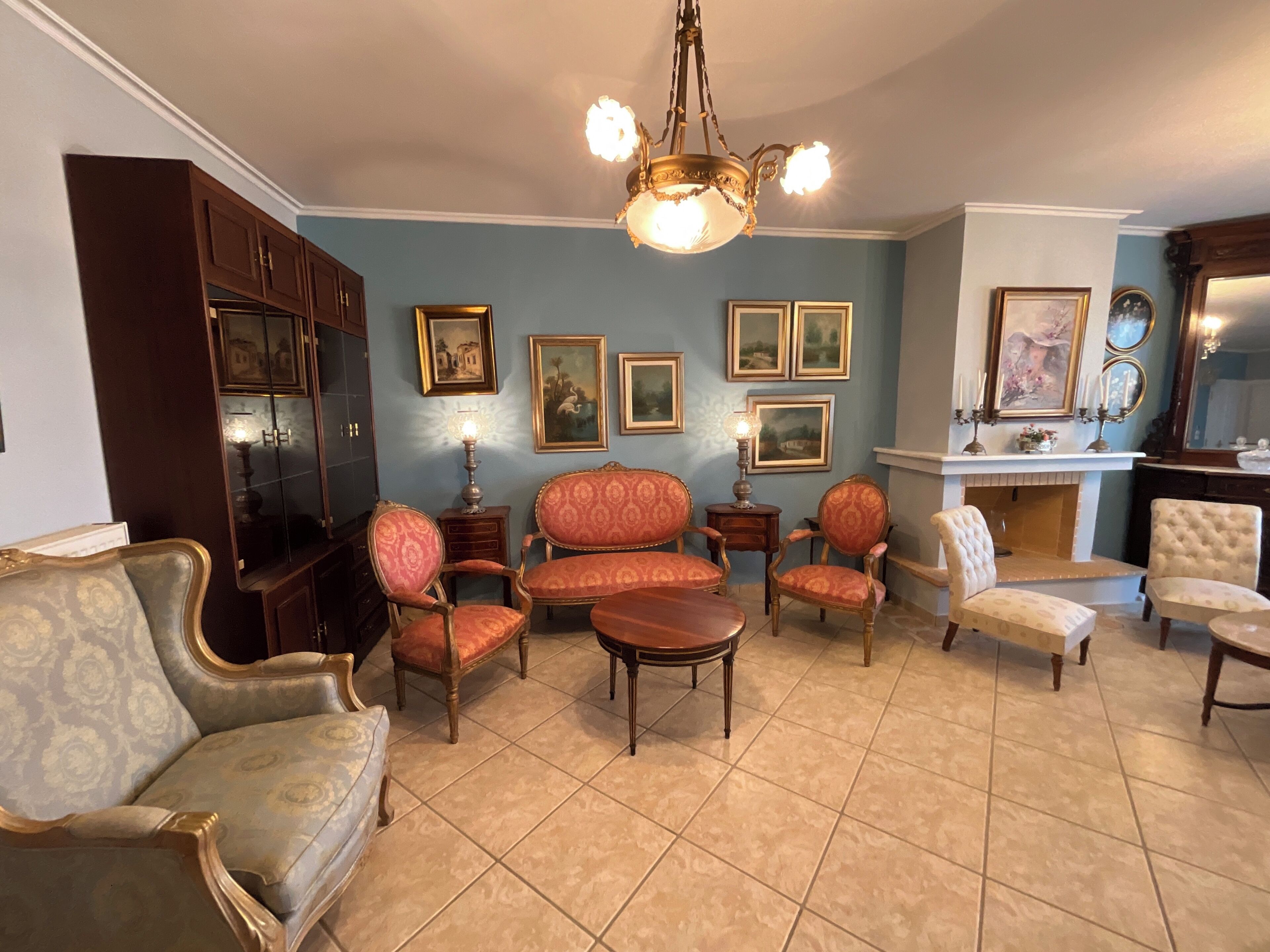 Un salon traditionnel avec une cheminée, de nombreux tableaux encadrés et des meubles classiques.