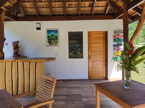 A wooden interior with a reception desk, a wooden door, and a wall-mounted sign with destination names. - FARE MANTA (Moorea-Maiao)