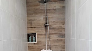 A shower area with a wooden panel wall, a handheld showerhead, and a wall-mounted faucet. - FARE MANTA (Moorea-Maiao)