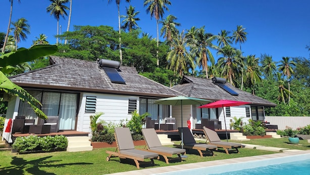 A resort with two guest houses, a swimming pool, and palm trees in the background. - FARE MANTA (Moorea-Maiao)